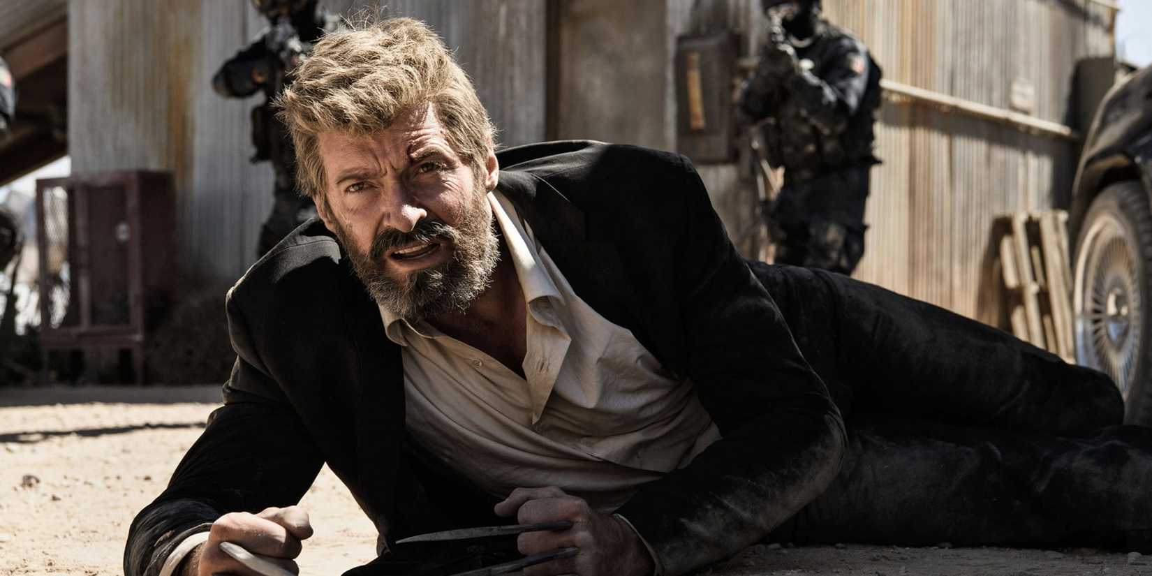 Hugh Jackman as Logan/Wolverine, wearing a suit and lying on the ground with his claws extended in 'Logan'.
