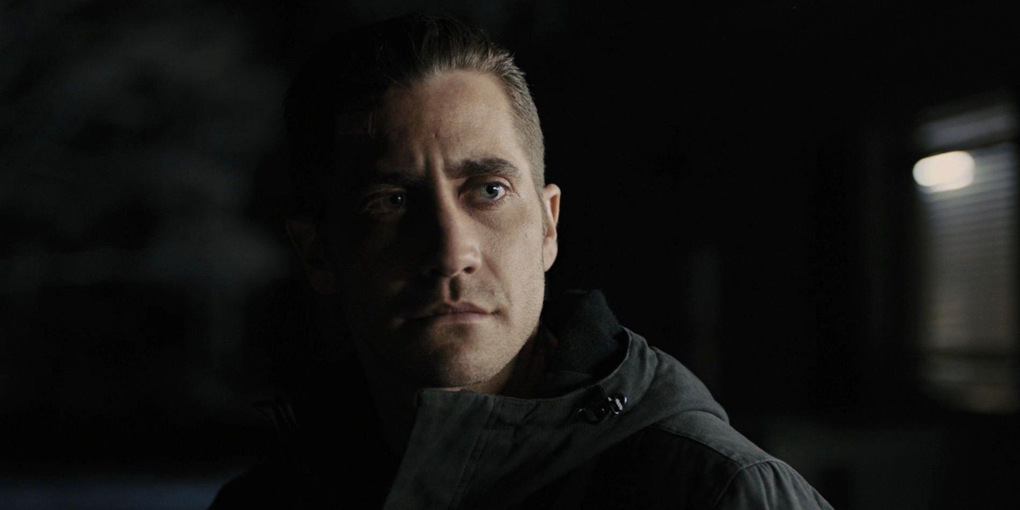Jake Gyllenhaal stands thinking in the dark in 'Prisoners' (2013)