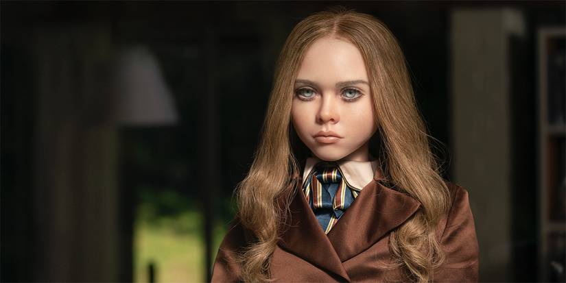 M3GAN in a brown coat staring at a person offscreen in M3GAN.