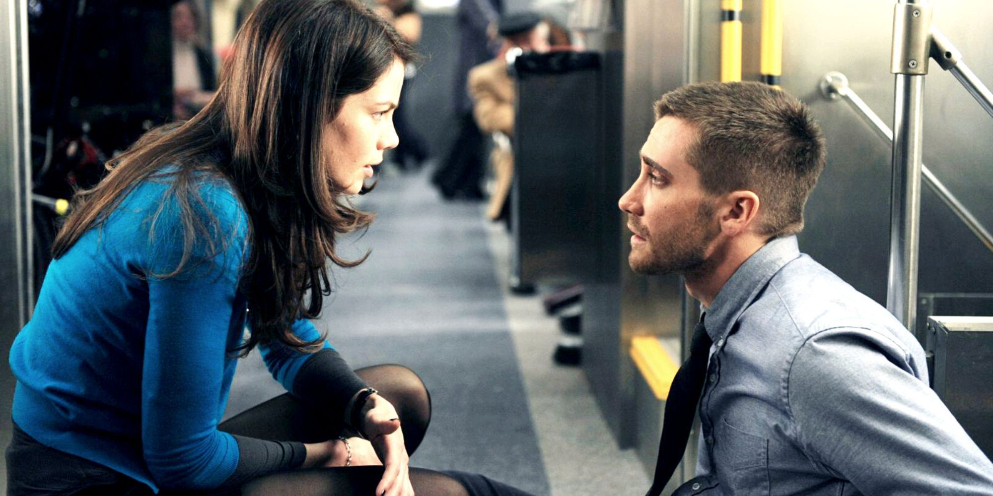 Michelle Monaghan crouching down in front of Jake Gyllenhaal sitting down on a train in Source Code