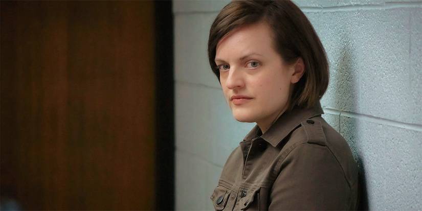 Elizabeth Moss looking to the side, sitting with her back against an interior brick wall in Top of the Lake.