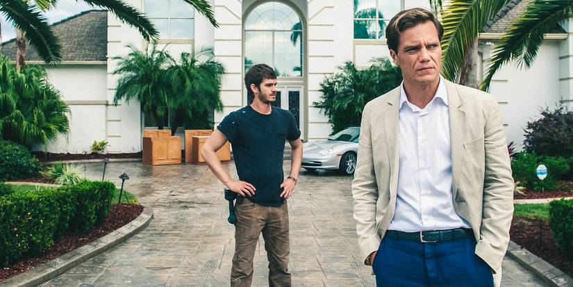 Michael Shannon as Rick Carver looks to the distance while Andrew Garfield as Denis Nash stands behind him in 99 Homes