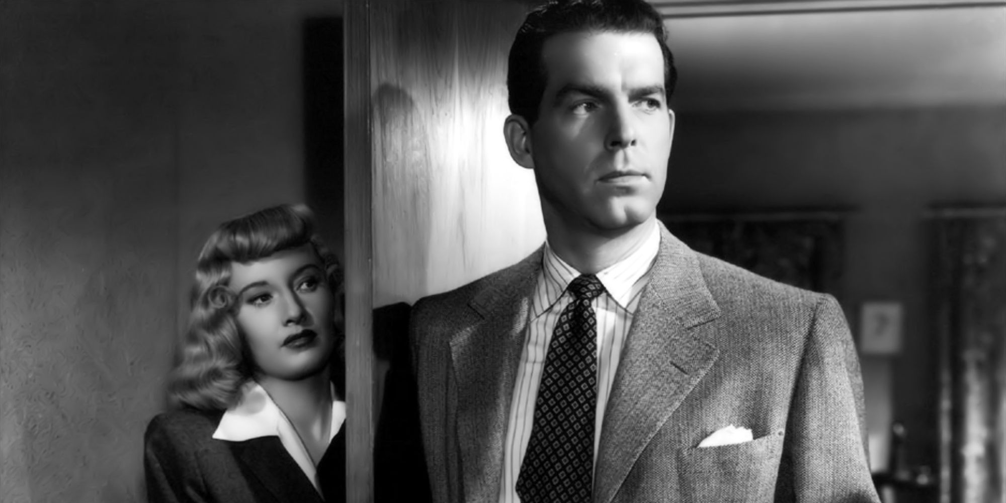Barbara Stanwyck standing behind a door as Fred MacMurray stands in the doorway in Double Indemnity.