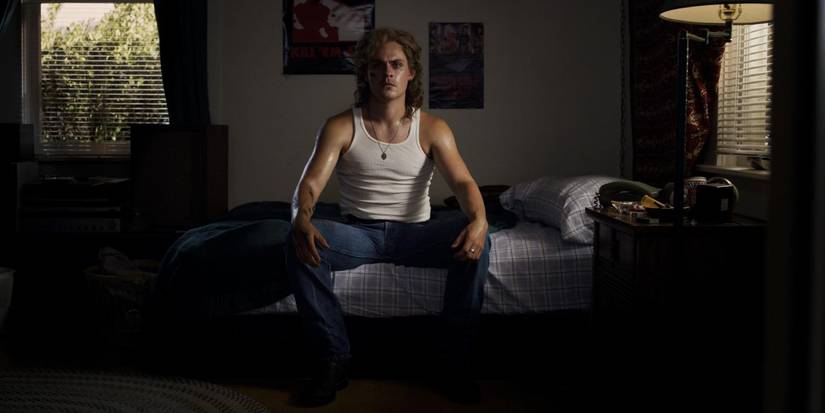 Dacre Montgomery as Billy sits on his bed after being possessed by the Mind Flayer in Stranger Things.