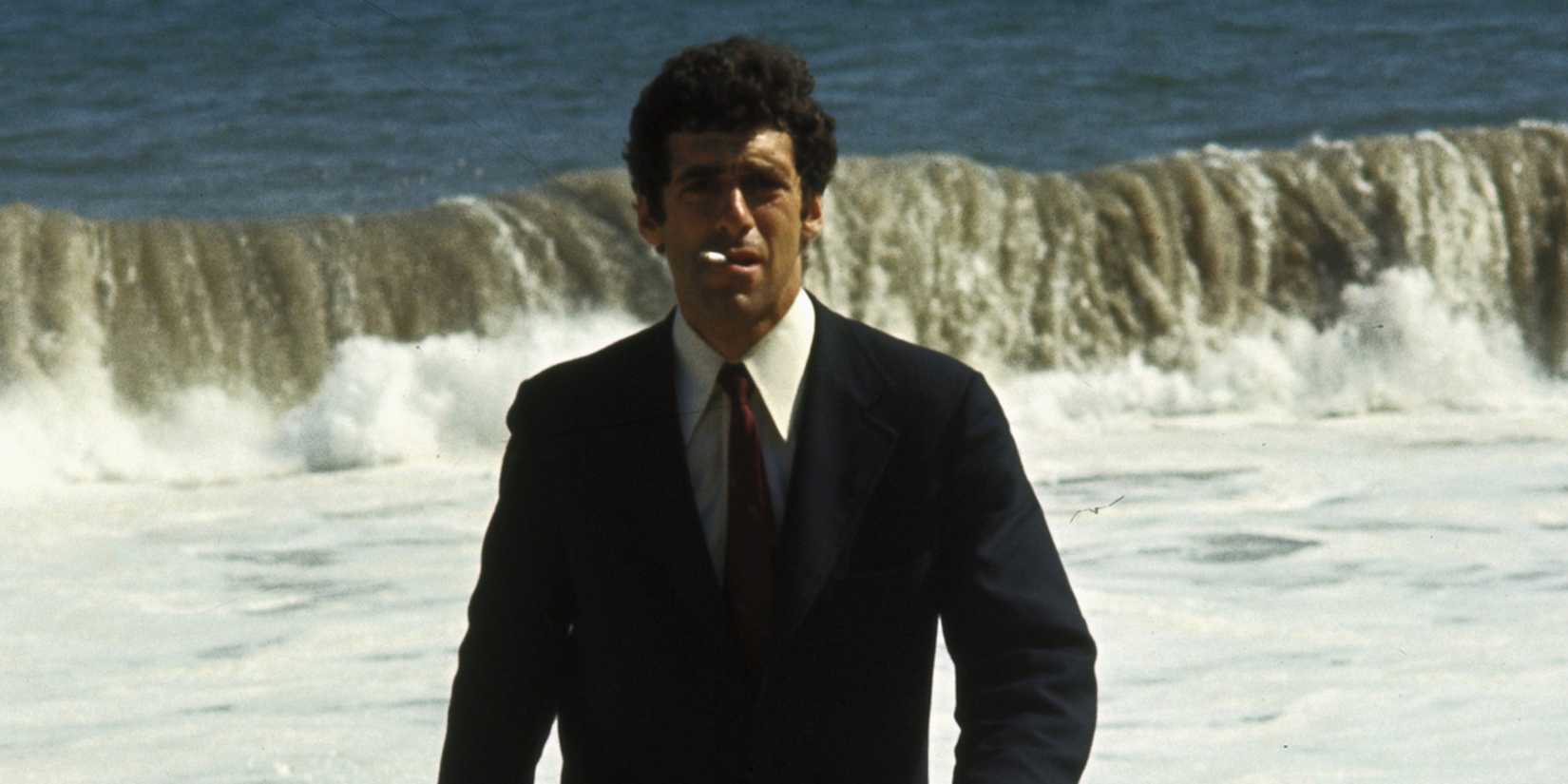 Elliott Gould smoking a cigarette walking in front of the ocean in The Long Goodbye