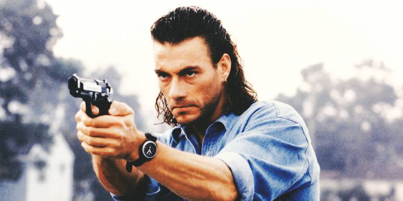 Jean-Claude Van Damme with a mullet haircut looks serious and holds a weapon in Hard Target.