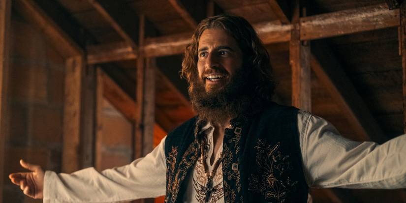 Jonathan Roumie as Lonnie Frisbee with his arms wide in a barn in Jesus Revolution 