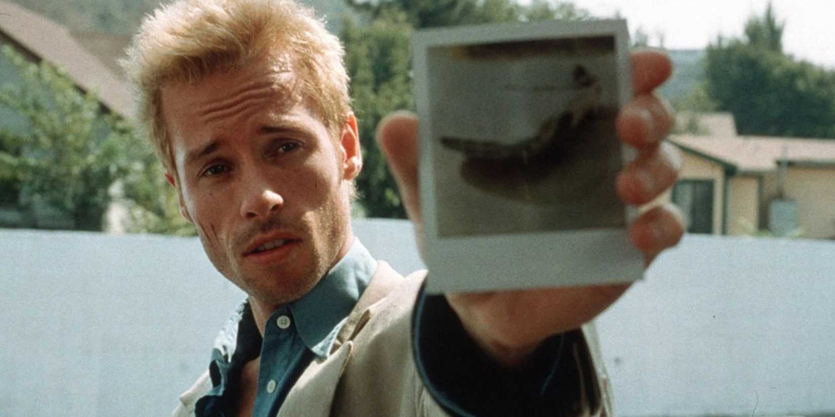 Guy Pearce holding out a polaroid photograph in Memento (2000)