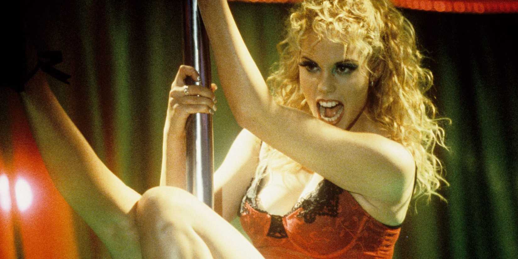 Elizabeth Berkley dances on stage with a pole in Showgirls.