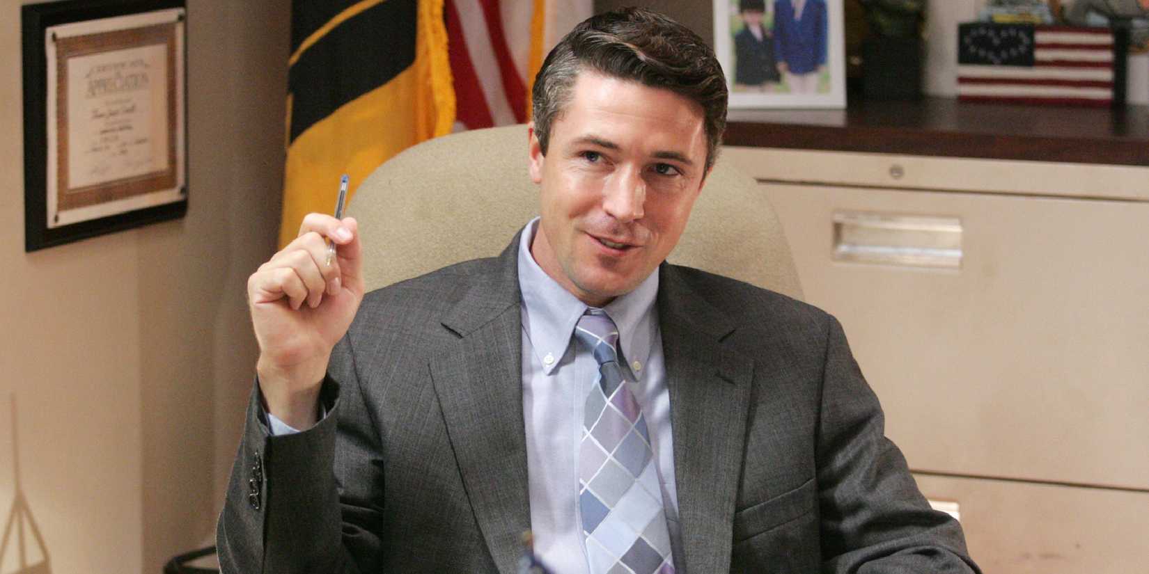 Aidan Gillen as Thomas Carcetti sitting at a desk in an office in The Wire.