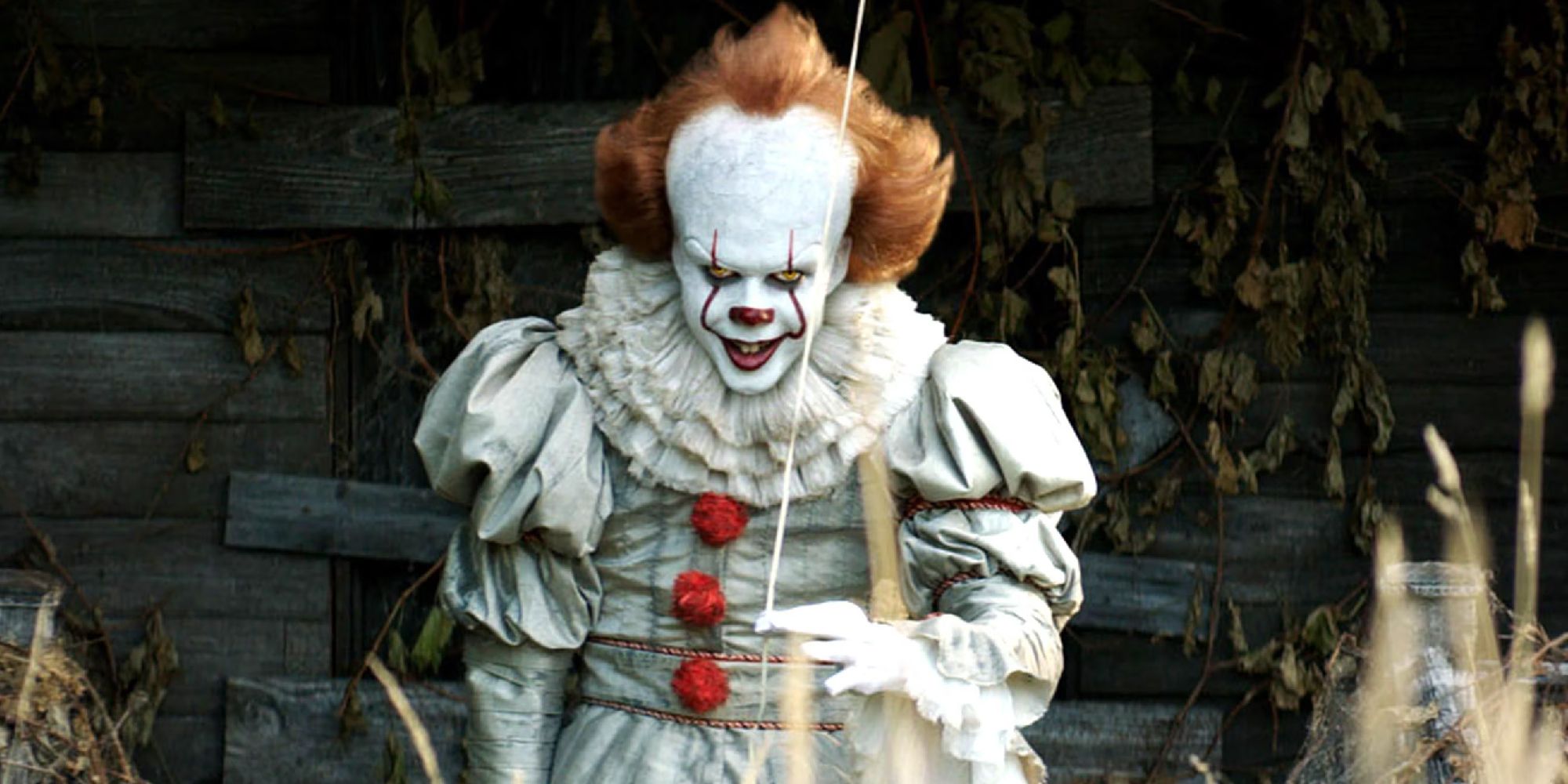 Pennywise (Bill Skarsgard) smiling while holding a balloon in 'It' 2017.