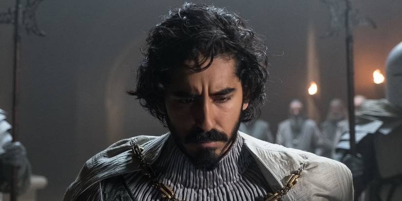 Dev Patel wearing an armor and looking down in image from 'The Green Knight'