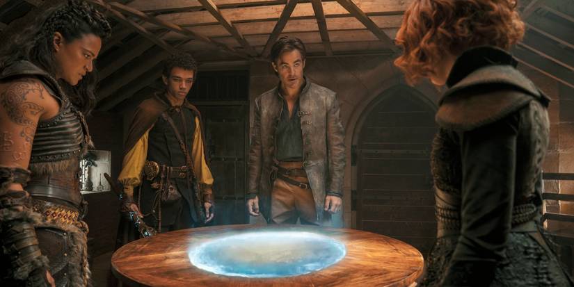 Michelle Rodriguez as Holga, Justice Smith as Simon, Chris Pine as Edgin, and Sophia Lillis as Doric standing around a table in Dungeons and Dragons: Honor Among Thieves