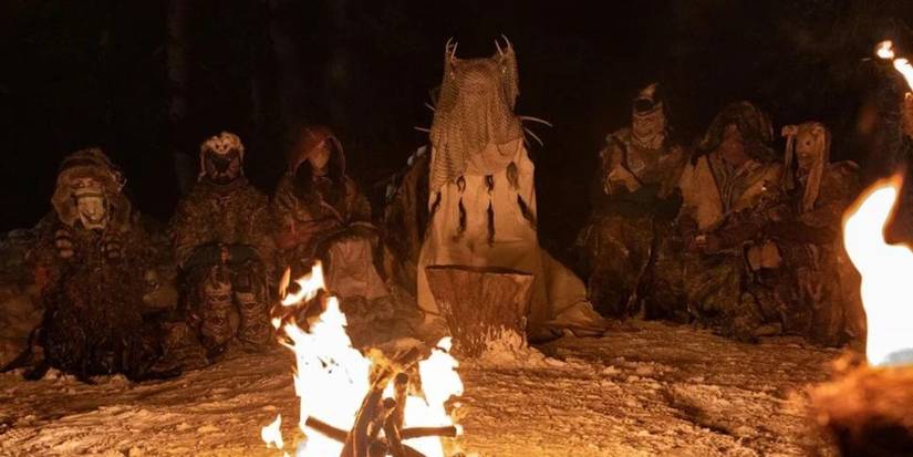 A group of masked individuals sitting in front of a fire in Yellowjackets.