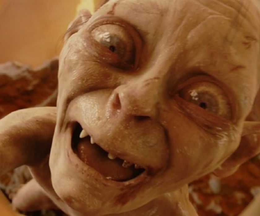 A still from The Return of the King of Gollum, played by Andy Serkis, smiling as he holds up the One Ring.