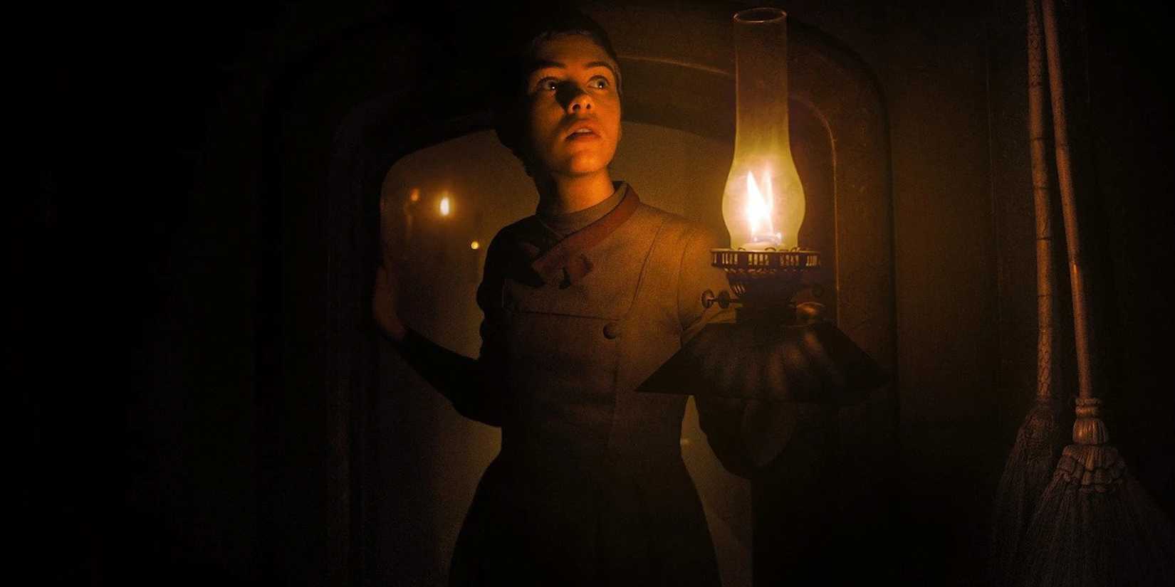 A young woman walking down a dark hallway holding a lamp in Gretel & Hansen