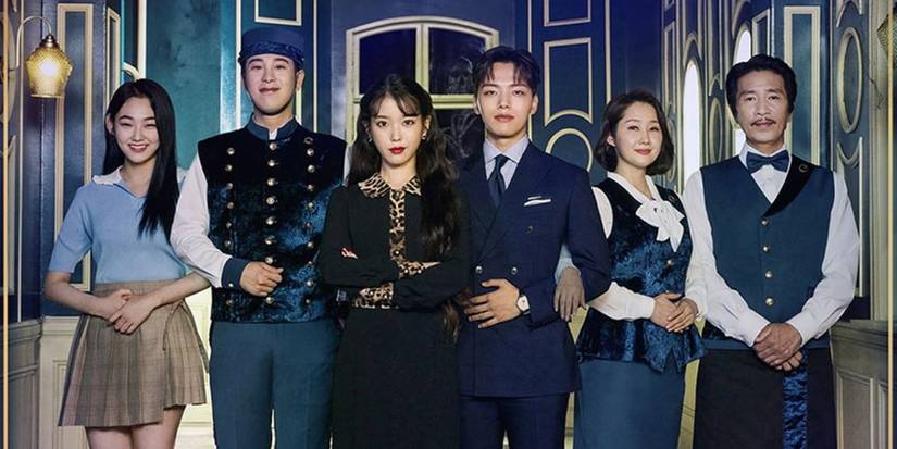 The Cast of Hotel del Luna standing together for a photo in hotel uniforms.