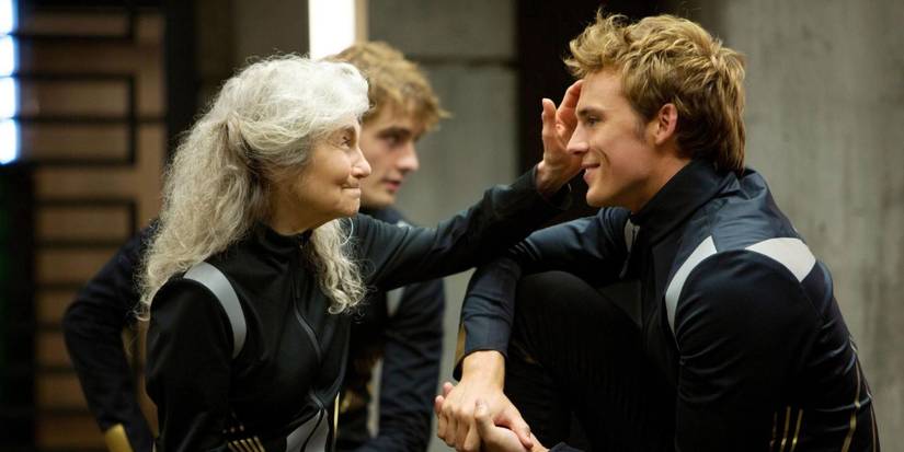 Finnick smiling at Mags as she smiles at him and touches his head in The Hunger Games: Catching Fire