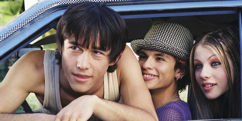 Joseph Gordon Levitt leans outside a car window with others in the car behind him smiling in Mysterious Skin