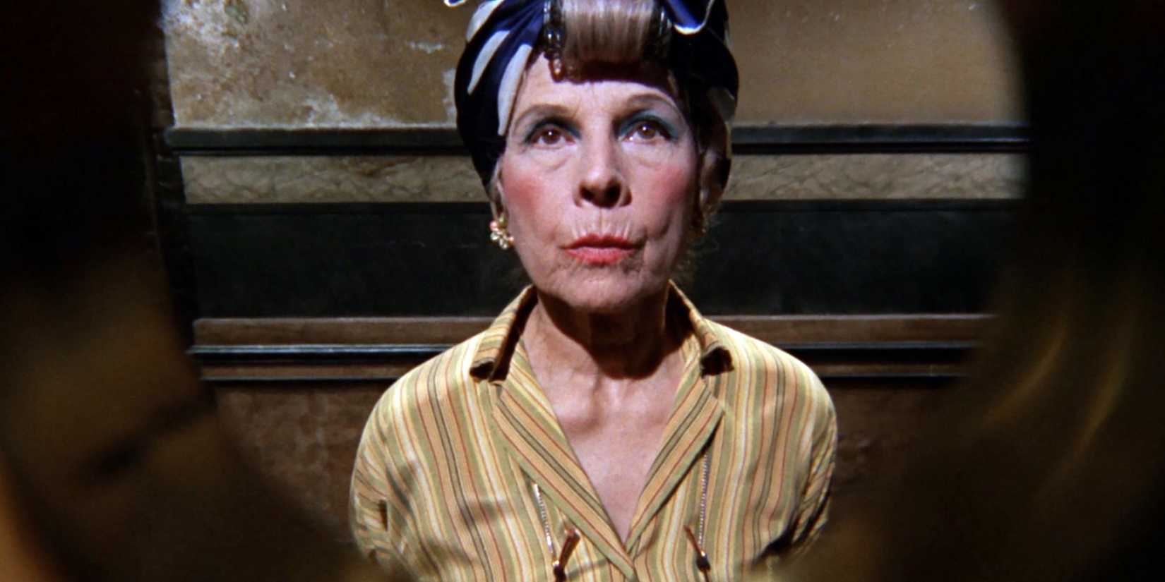 Ruth Gordon as Minnie Castevet stares through a peephole at the camera in Rosemary's Baby
