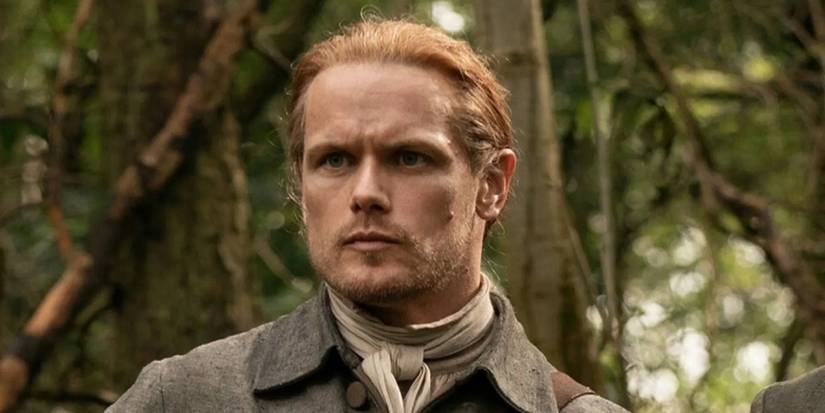 Sam Heughan as Jamie Fraser wearing a dark grey suit in 'Outlander.'