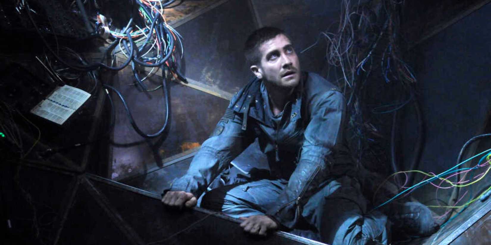 Jake Gyllenhaal as Captain Colter Stevens sitting in a ruined building in Source Code