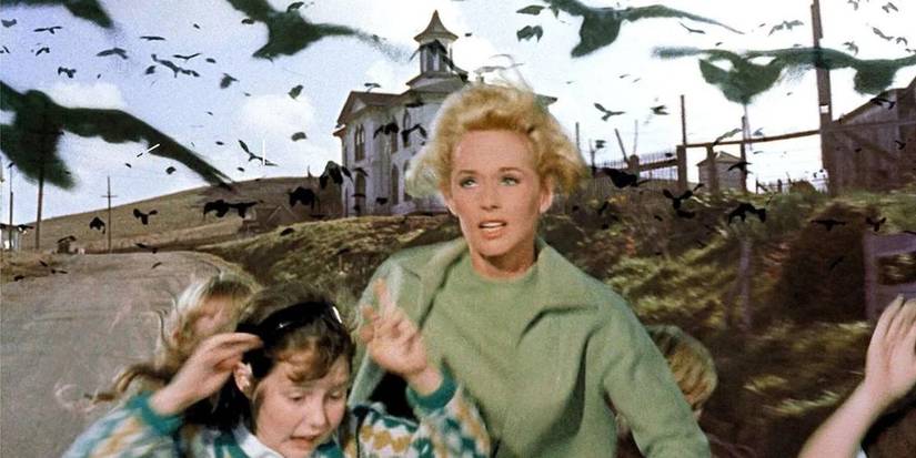 Melanie, played by Tippi Hedren, running with a little girl away from a swarm of attacking birds in Alfred Hitchcock's The Birds