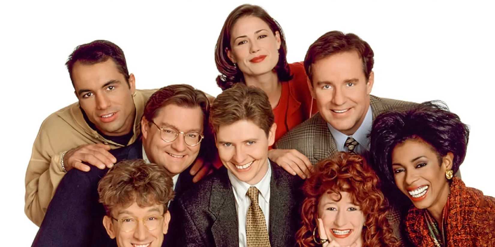 The cast of Newsradio smiling in front of a white background in a promotional shoot for the series.