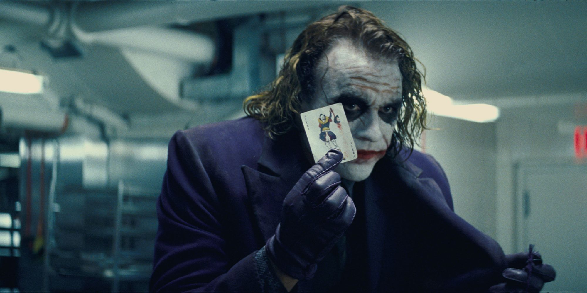 The Joker showing a Joker card in The Dark Knight