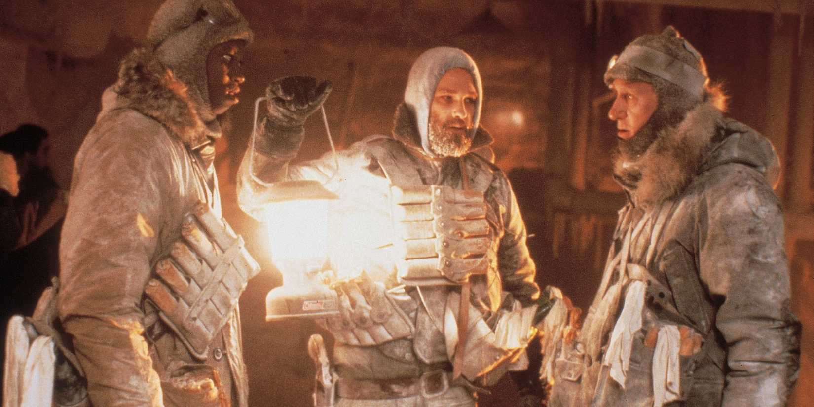 Macready (Kurt Russell) holding a lantern with other researchers in a snow mine from 'The Thing' (1982).
