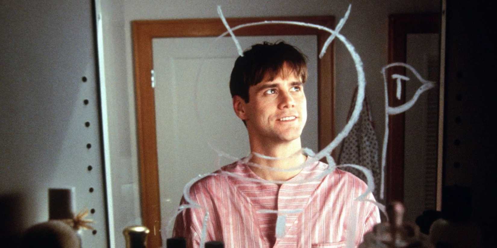Jim Carrey as Truman standing in front of a drawn mirror and smiling in 'The Truman Show'.