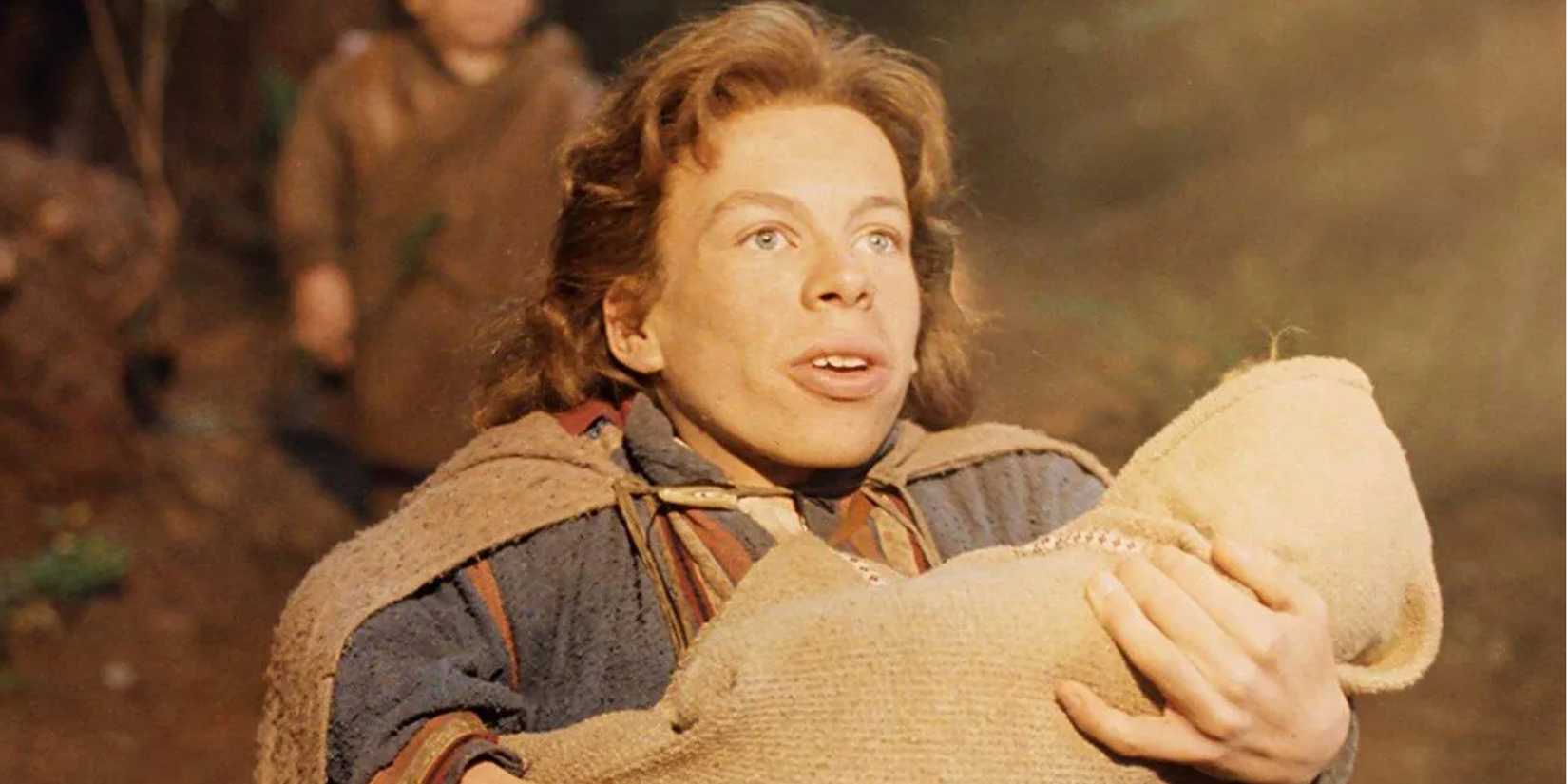 Willow, in the woods, holds a human baby swaddled in a blanket