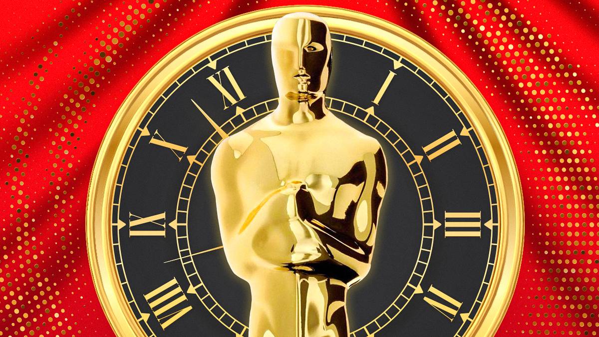 A picture of an Oscar statue in front of a clock and a red curtain.