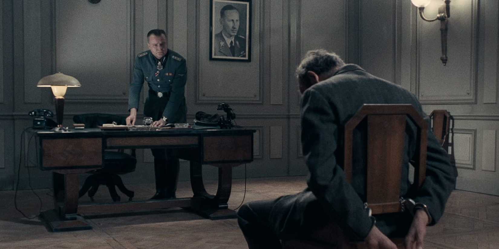 A man tied to a chair sits and a man sitting a desk in 'Army of Shadows'