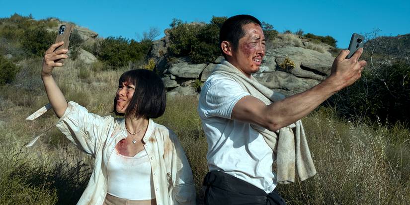 Ali Wong and Steven Yeun as Amy and Danny checking their phones for reception while in the wild in Beef