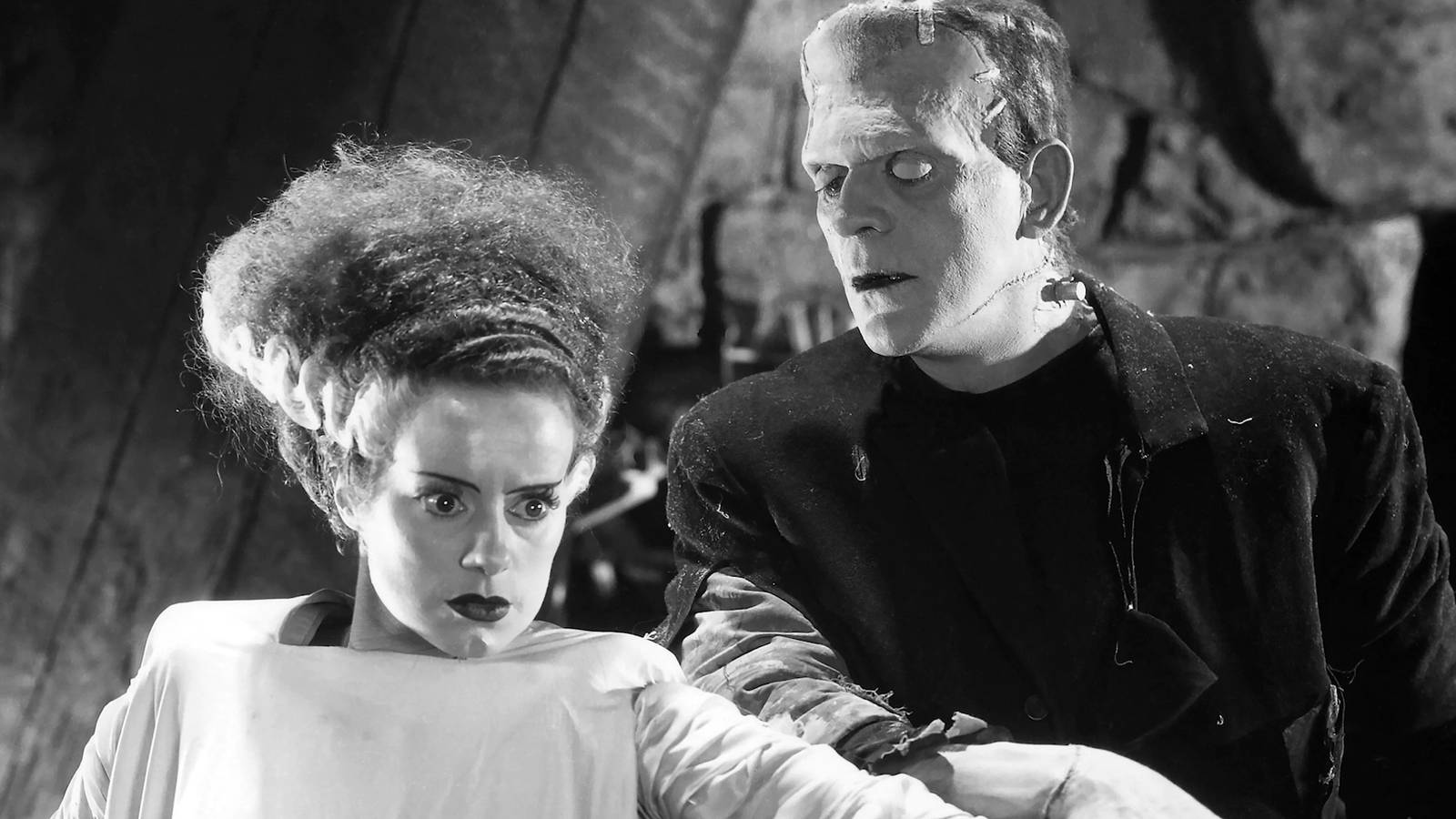 Frankenstein's Monster looks at his bride, and she looks off camera with a confused look on her face in The Bride of Frankenstein.