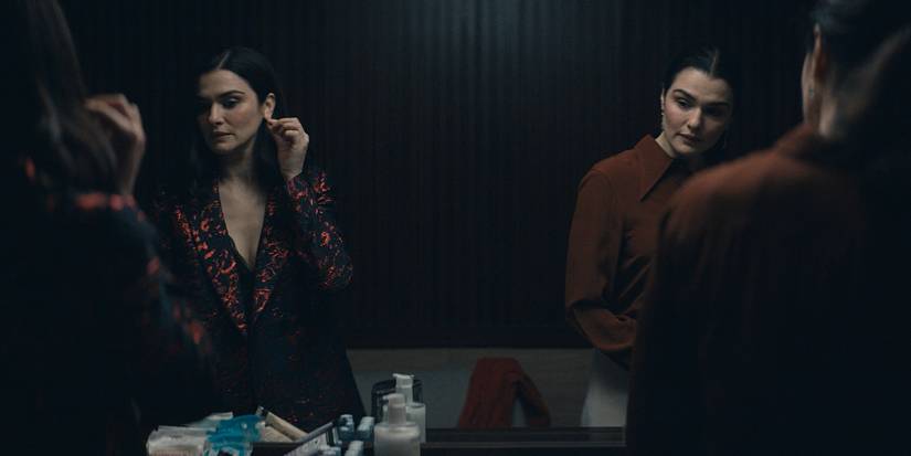 Rachel Weisz as twin characters standing in front of a mirror, their reflections visible in a scene from Dead Ringers.
