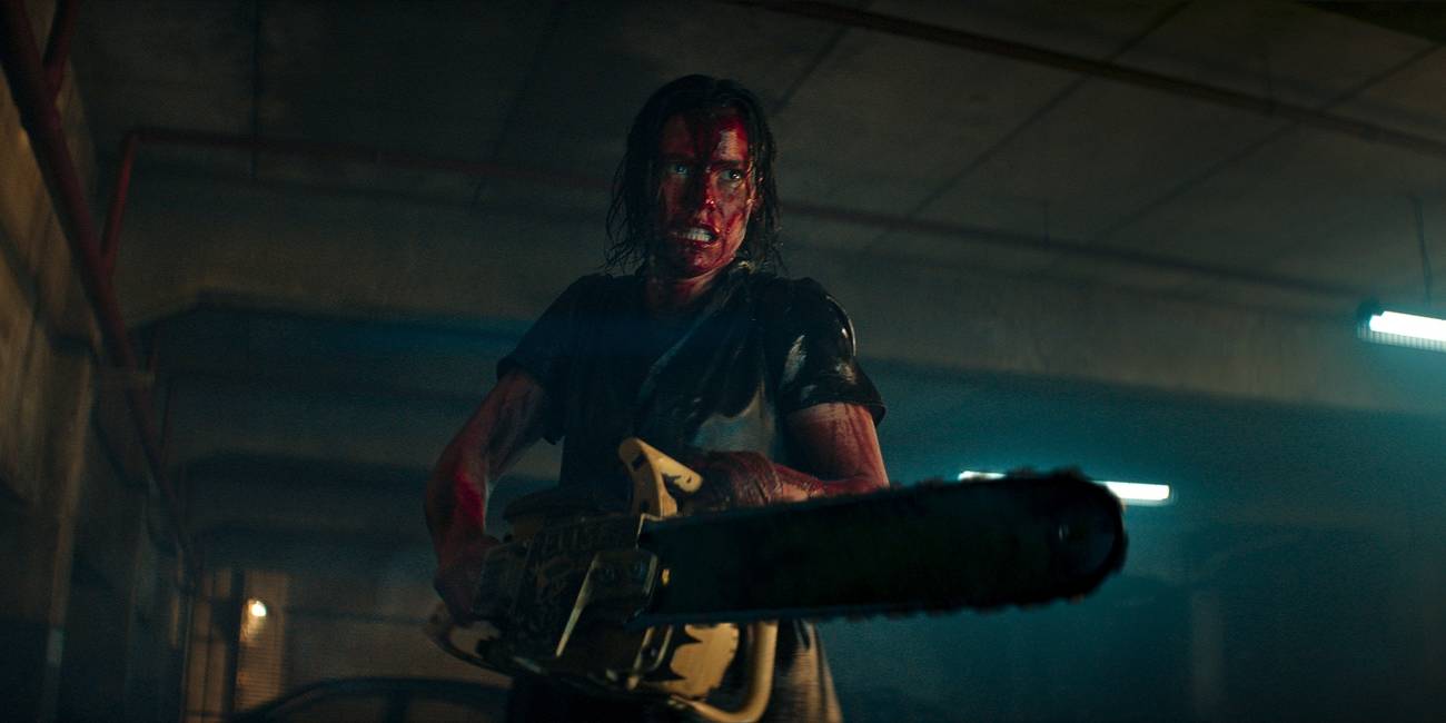Lily Sullivan as Beth, covered in blood and wielding a chainsaw in Evil Dead Rise