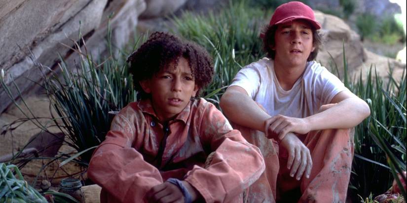 Shia LaBeouf como Stanley y Khleo Thomas como Héctor sentados en el césped de Disney's Holes.