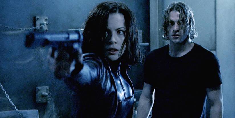 Kate Beckinsale as Selene points a weapon with Scott Speedman as Michael behind in Underworld.