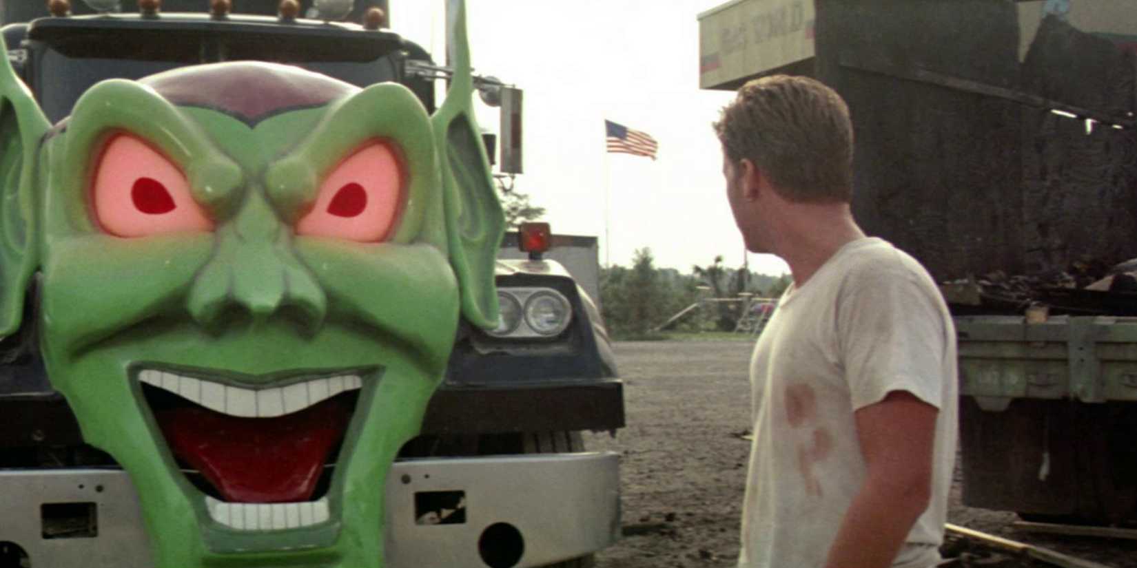 A young man looking at a truck with a green face on it in Maximum Overdrive.