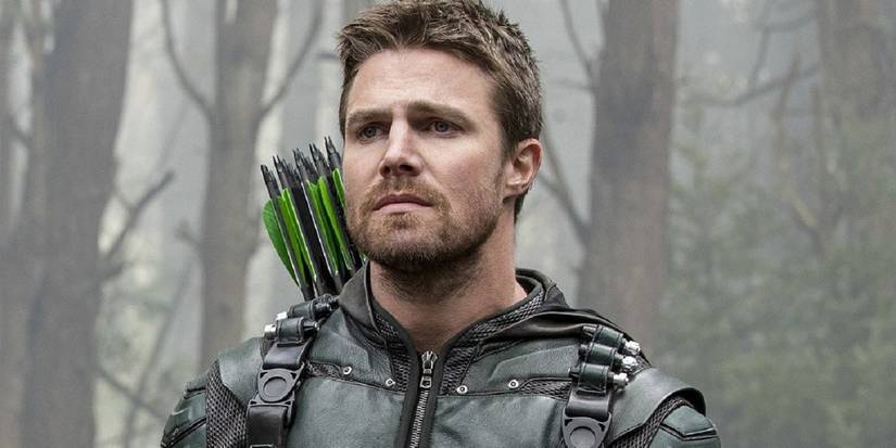 Oliver Queen in his Green Arrow suit looking intently ahead while in a misty forest.