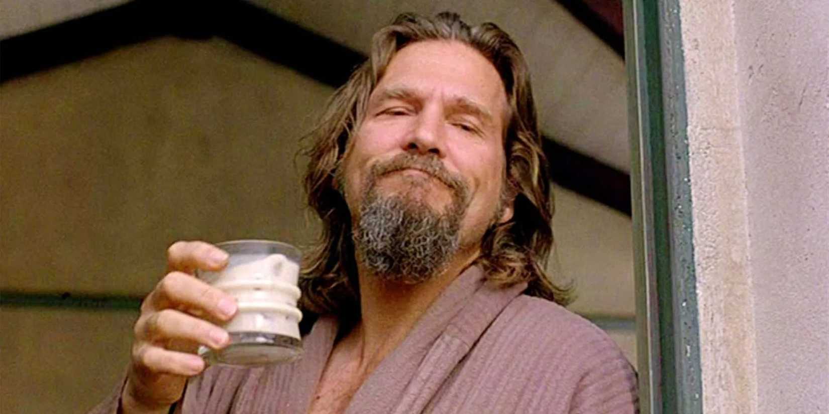 Jeffrey "the Dude" Lebowski (Jeff Bridges) stands in a doorway wearing a dressing gown and holding a drink.