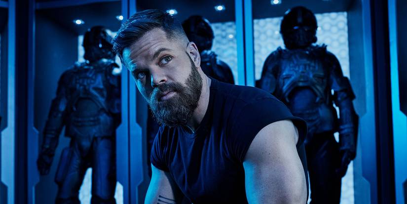 Wes Chatham as Arnos Burton sitting down looking offscreen in The Expanse.