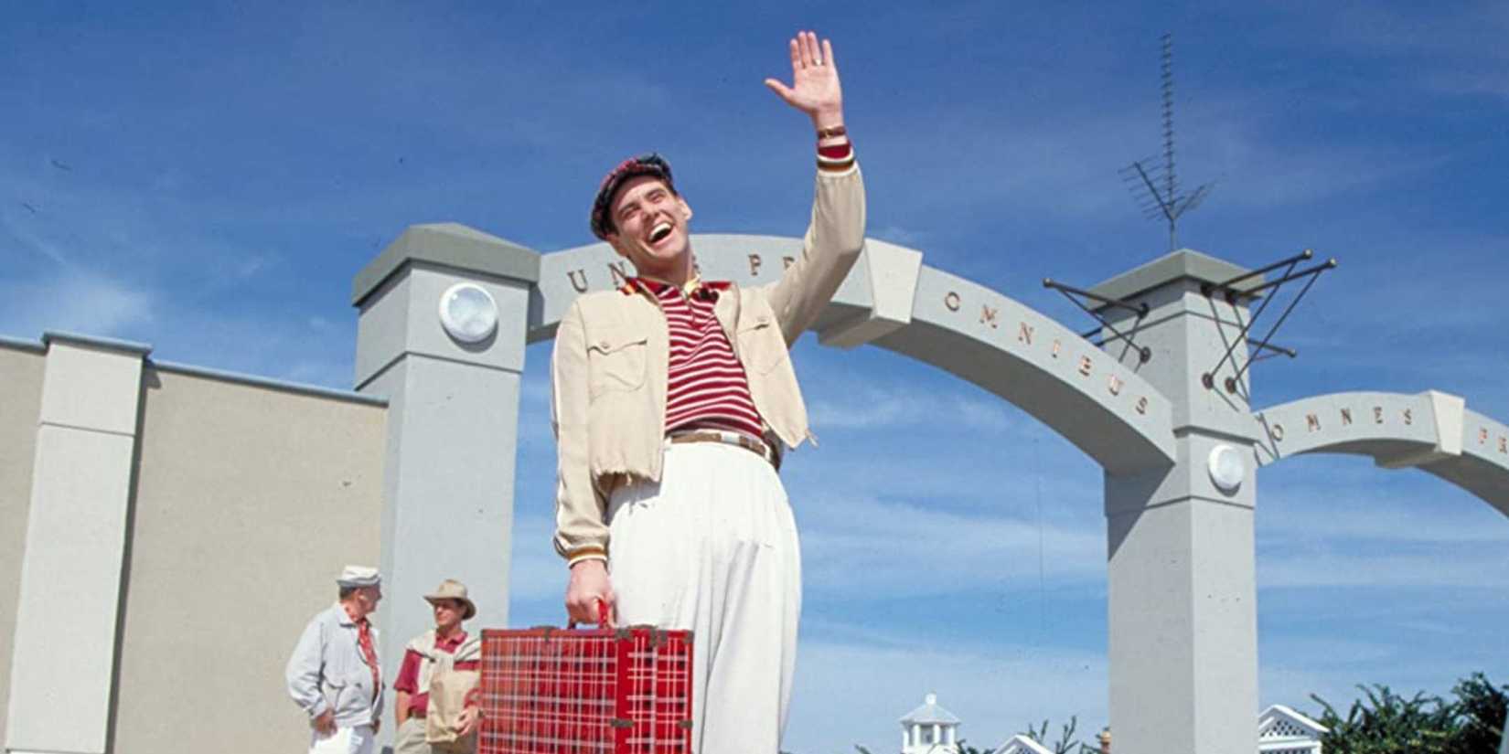 Jim Carrey as Truman Burbank smiling and waving at someone off-camera in The Truman Show.