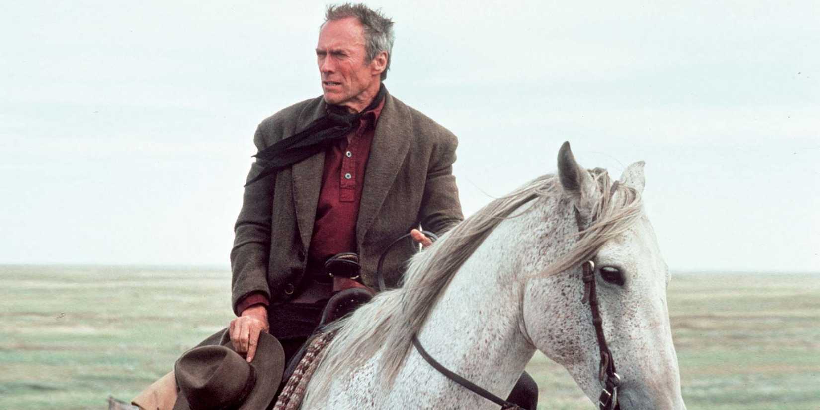 Clint Eastwood as Will Munny, riding a white horse in Unforgiven.