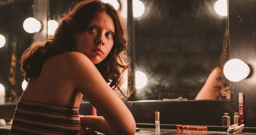 Mia Goth as Maxine sitting in front of a mirror in X
