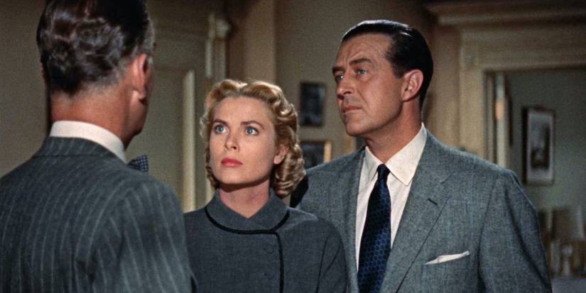Ray Milland and Grace Kelly looking at a man not facing camera in Dial M for Murder