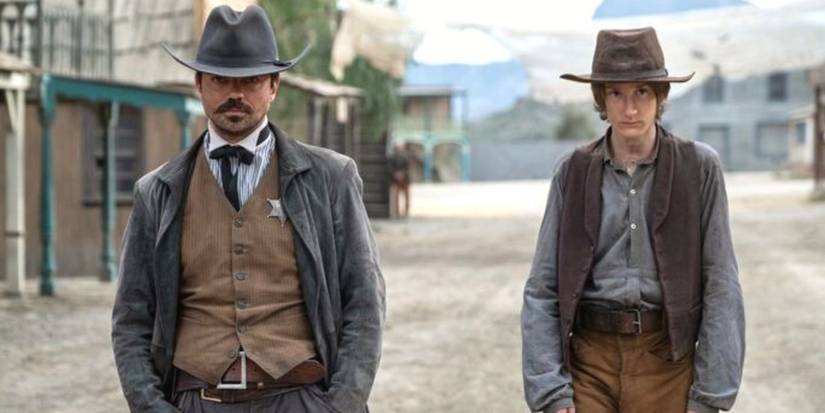 Dominic Cooper standing with a young man in a deserted street in That Dirty Black Bag.