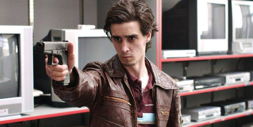 James Ransone as Ziggy in 'The Wire', pointing a gun in front of screens in a store